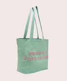 Light blue tote bag with pink text on a pink background