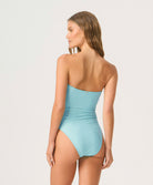 Woman wearing a light blue strapless swimsuit against a white background