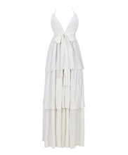 A white floor length dress against a white wall. 