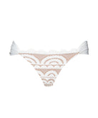 A white lace bikini bottom against a white wall.