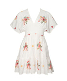 A short sleeve dress with floral details against a white wall.