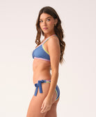 Woman wearing a blue bikini with colorful trim on a white background