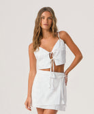 Woman wearing a white outfit with cut-out design on a plain background