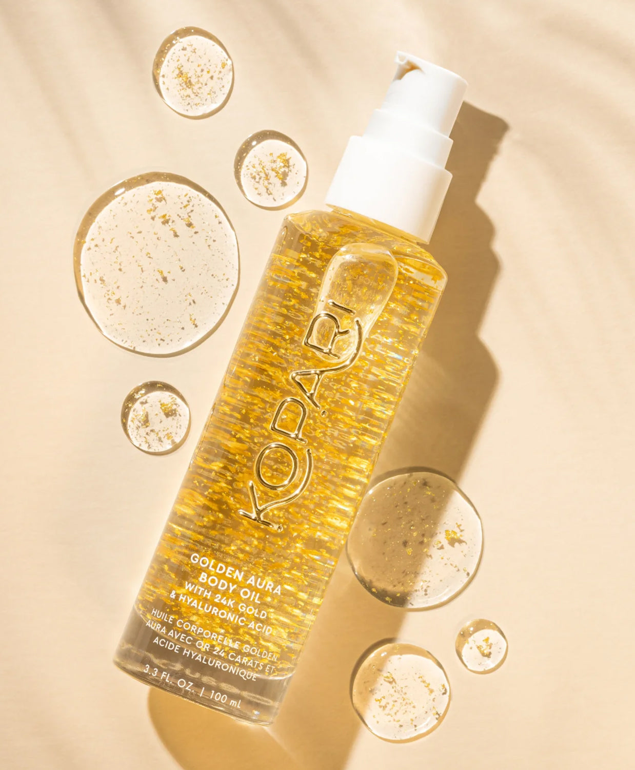 A tube of body oil with gold pieces against a yellow wall.