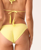 Woman wearing a yellow bikini with tassels on a white background