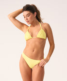 Woman wearing a yellow triangle top bikini against a plain background