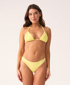 Woman wearing a yellow triangle bikini against a plain background