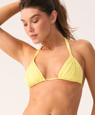 Woman wearing a yellow triangle bikini top against a plain background