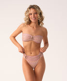 Woman wearing a pink bandeau bikini with a white background