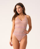 Woman wearing a pink patterned swimsuit on a white background