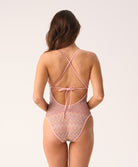 Woman wearing a pink patterned one-piece swimsuit on a white background