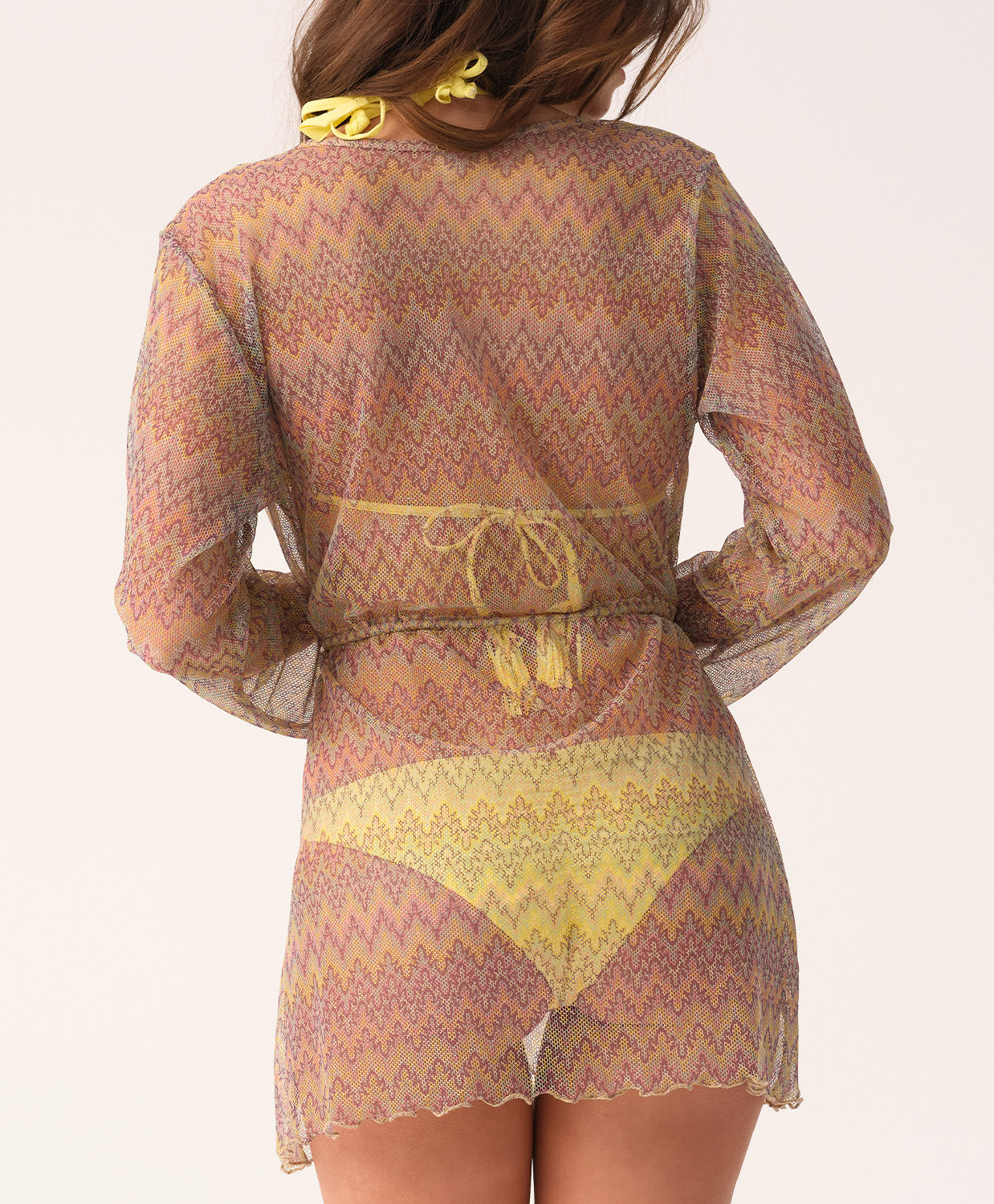 Woman wearing a patterned sheer outfit with a belt on a light background