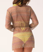 Woman wearing a patterned sheer outfit with a belt on a light background