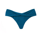 A textured turquoise bikini bottom with crisscross front detail. Featured against a white wall background.