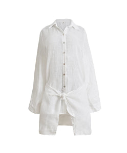 A lightweight white linen button coverup with front-tie detail. Featured against a white wall background.