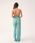 view of a woman from behind wearing a bikini and matching blue high waisted pant on a white background.