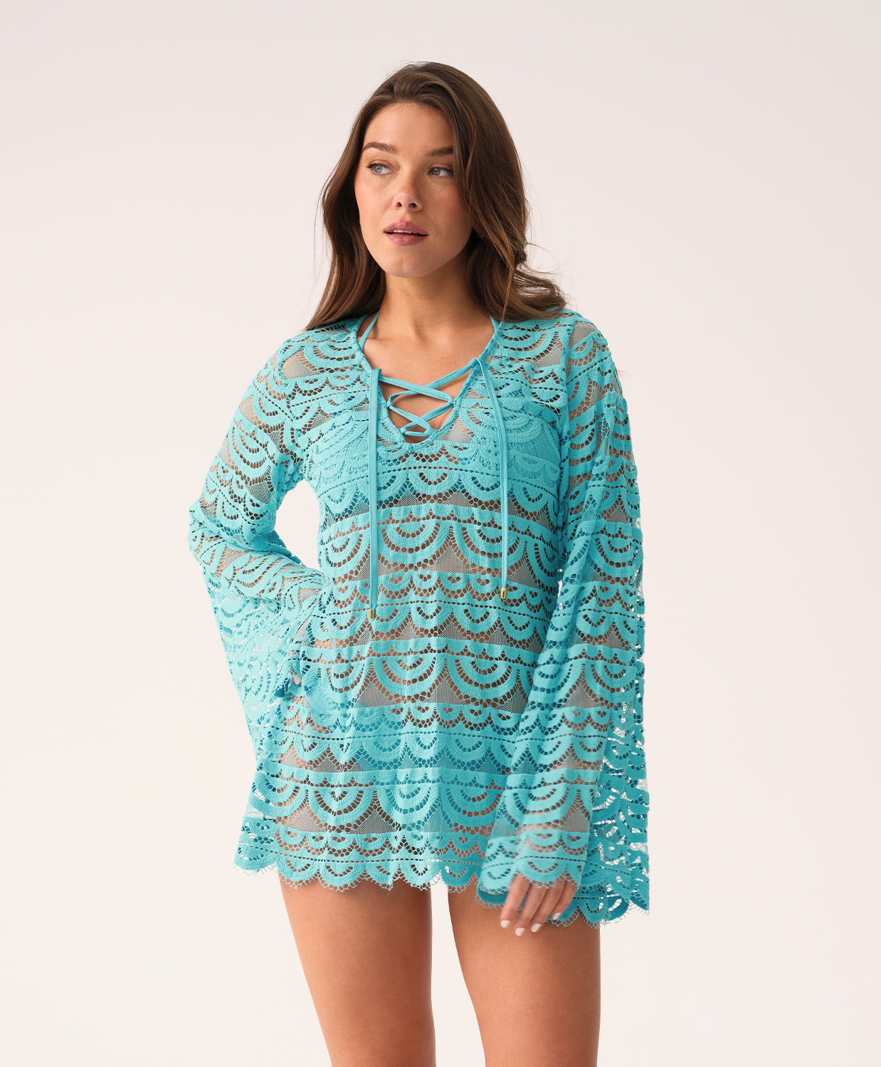 Front view of a woman modeling a light blue lace tunic with long bell sleeves and a lace-up neckline.