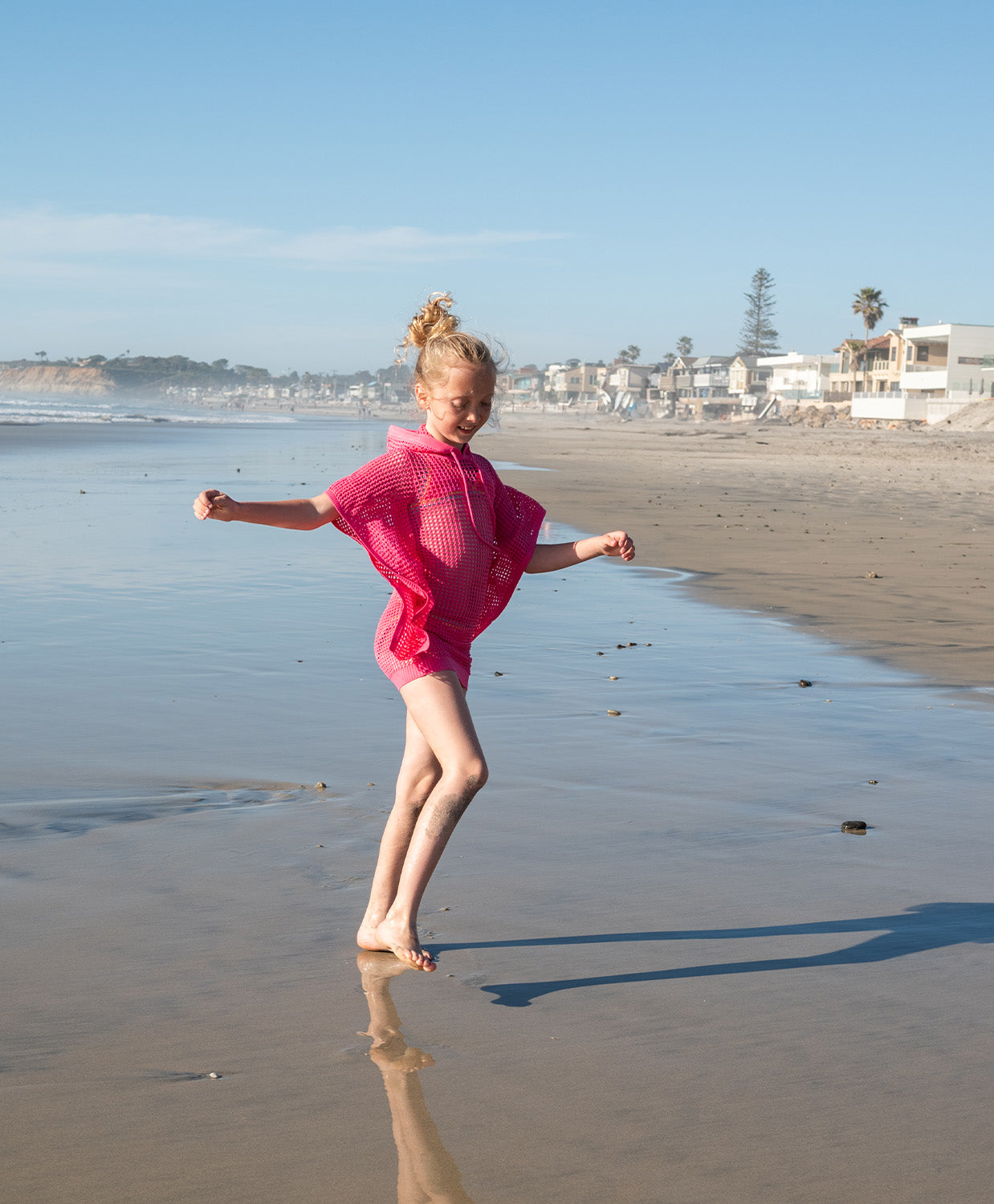 Kids Hot Pink Reagan Poncho with cozy hood and drawstrings, perfect for breezy beach days and post-swim comfort.