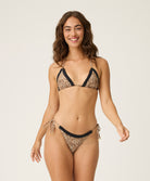 Woman wearing a leopard print bikini with black lace trim on a white background