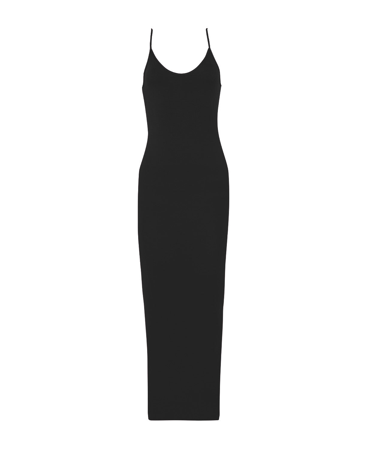 A woman wearing a long black slip dress standing against a white wall.