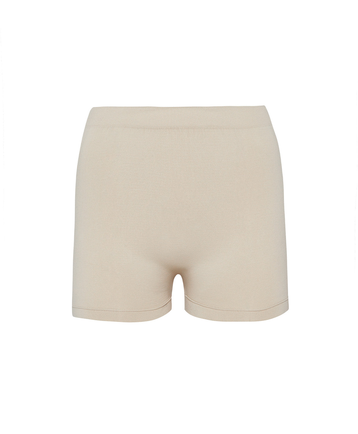 A woman wearing a nude bandeau and matching shorts standing against a white wall.