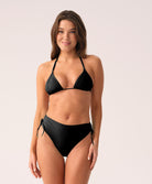 A woman wearing a black bikini with high waist bottoms against a white background