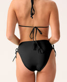 A woman wearing a black bikini with high waist bottoms against a white background