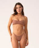 Woman wearing brown bikini set with gold hardware detail against white background.