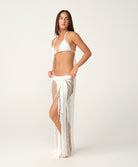 Woman wearing a white bikini and matching sheer skirt on a white background