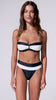 A woman wearing a navy and white color block bandeau bikini spinning against a white wall.