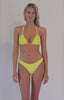 Blonde woman wearing a yellow macrame bikini spinning in front of a white background.  