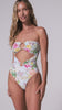 A woman wearing a light blue floral one piece swimsuit spinning against a white wall. 