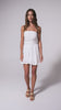 A woman wearing a short white flowy dress spinning in front of a white background.