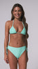 A woman wearing a blue triangle top bikini and matching high waist bottoms spinning in front of a white wall.