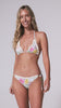 A woman wearing a light blue floral bikini set with a white crochet knit trim spinning in front of a white wall. 