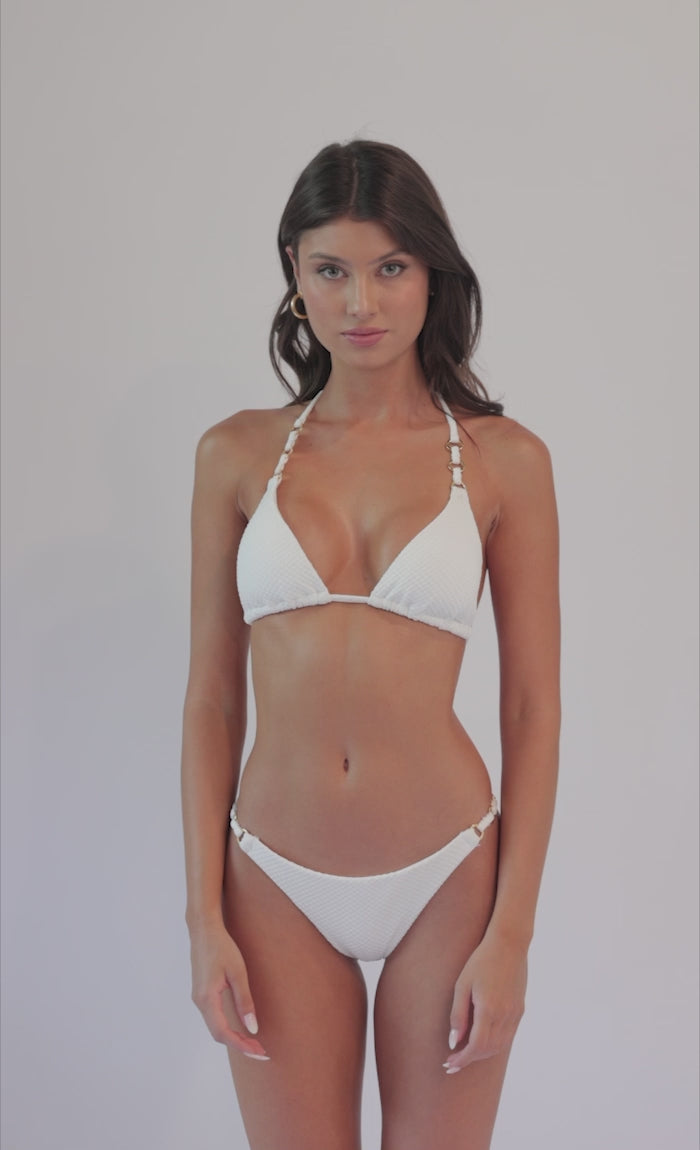 Brunette woman wearing a white bikini spinning in front of a white background. 