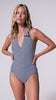 A woman wearing a blue and white striped one piece swim suit spinning in front of a white wall.