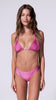 A woman wearing a pink triangle top bikini spinning in front of a white wall.