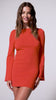 A woman wearing a long sleeve red mini dress spinning against a white wall. 