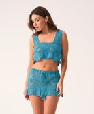 Woman wearing a blue crochet two-piece set on a white background