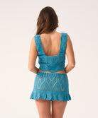 Woman wearing a blue crochet top and skirt set on a white background