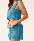 Woman wearing a blue crochet top and skirt set on a white background