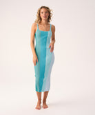  A woman wearing a blue vertical-striped dress standing in front of white background. 