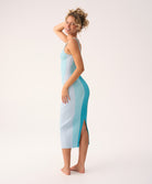 Woman wearing blue vertical-striped dress standing in front of white background at an angle. 