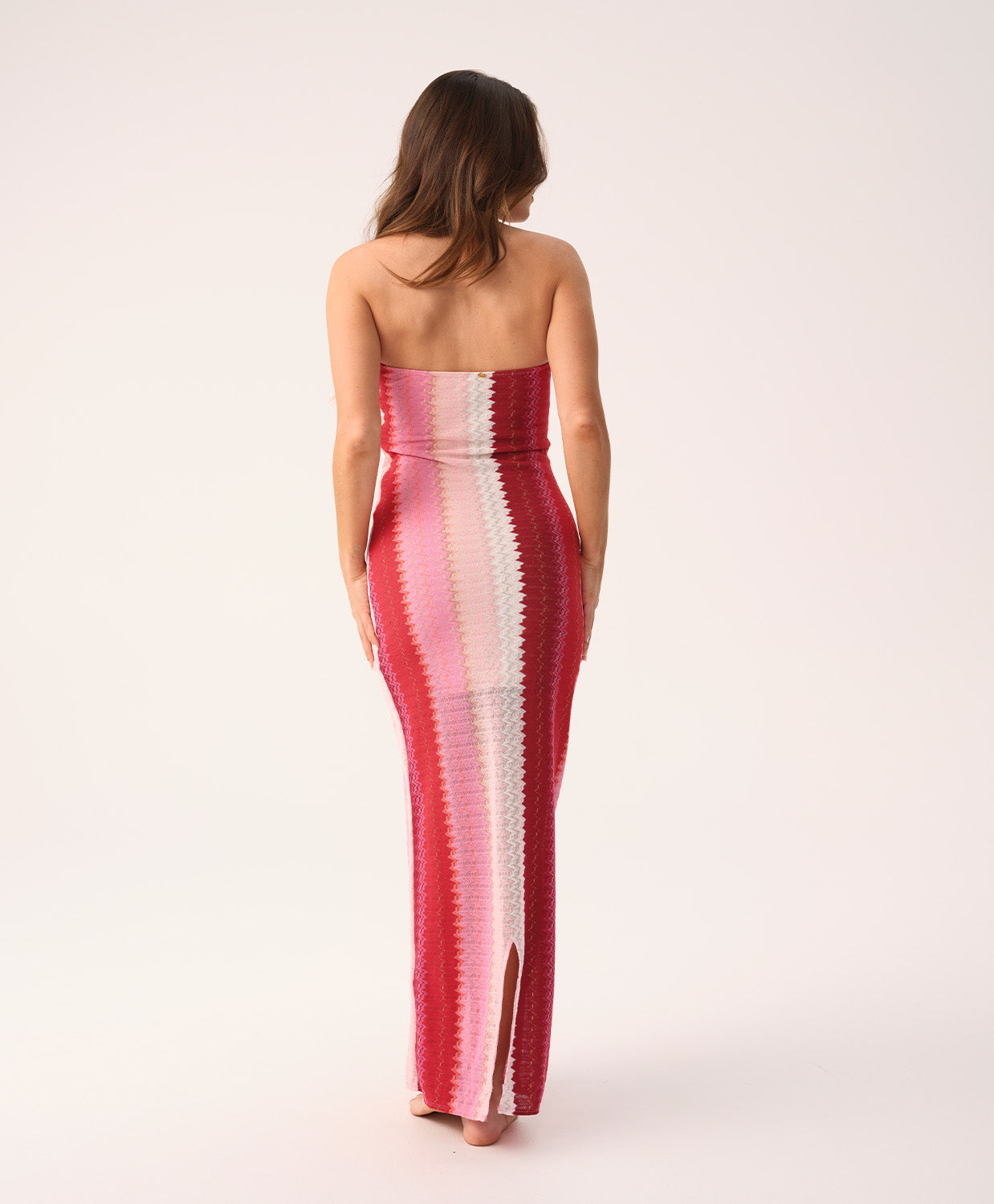 Scarlet Jane strapless dress with vibrant pink, red, and white chevron pattern and gold lurex shimmer, featuring a back slit.