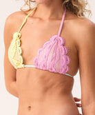 Close-up of a pink and yellow lace bikini top on a woman against a neutral background