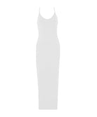 A woman wearing a white long slip dress standing in front of a white wall.