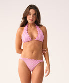 Woman wearing a pink lace bikini against a white background