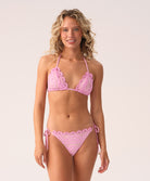 Woman wearing a pink lace bikini against a white background