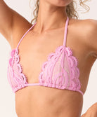 Woman wearing a pink lace bikini top on a white background.